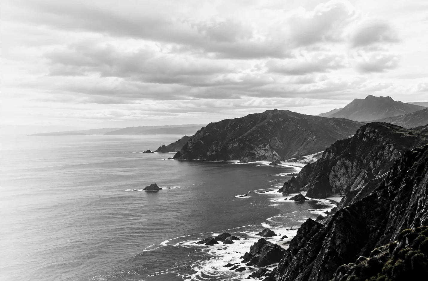A rugged Atlantic coastline under a red sun, cliffs fading into the mist