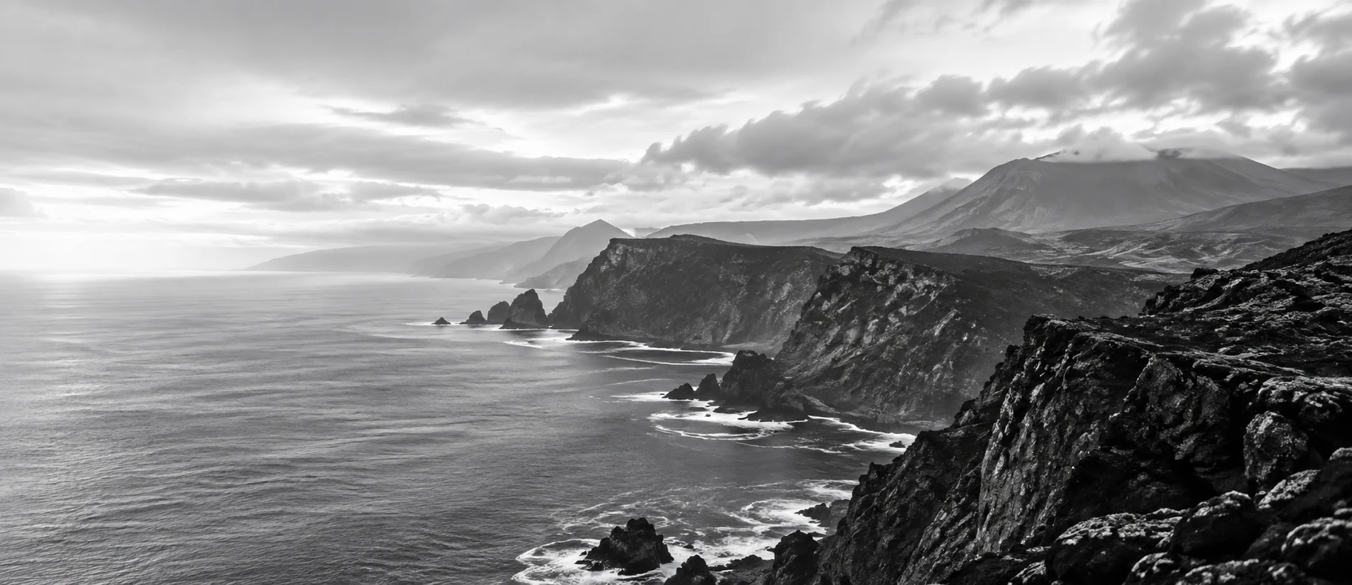 Sea cliffs of the Azores under a bright, clouded sky